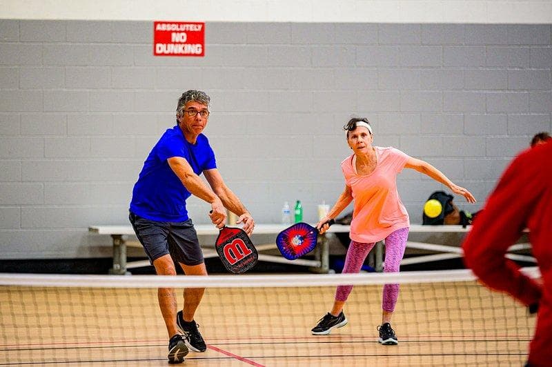 Older couple playing doubles indoors