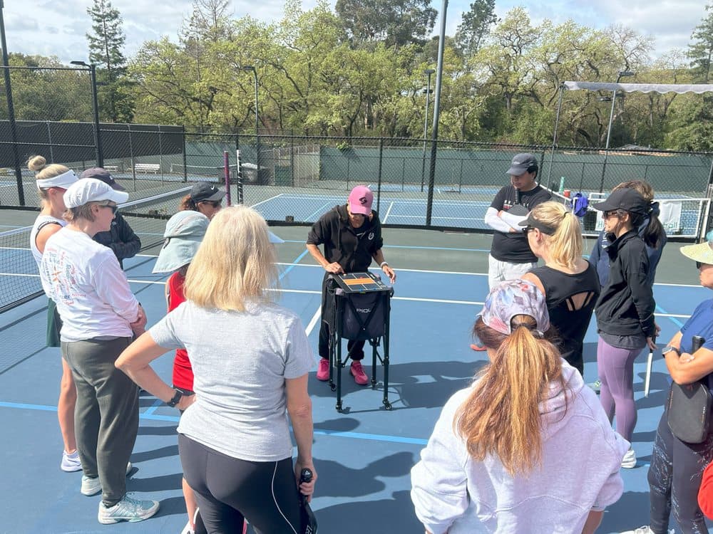 A camp group huddled around the coach on court
